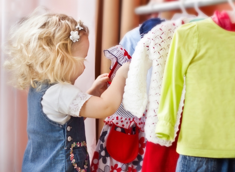 Adorable little girl choosing clothes